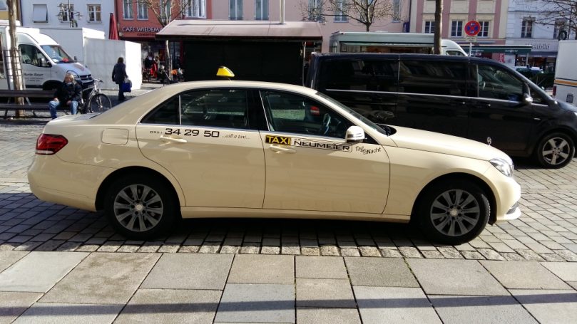 Gelbes Taxi steht an der Straßenseite, in einer urbanen Umgebung.